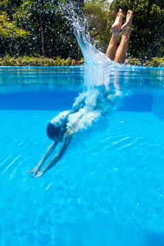 Woman dives underwater into a luxury resort swimming pool
