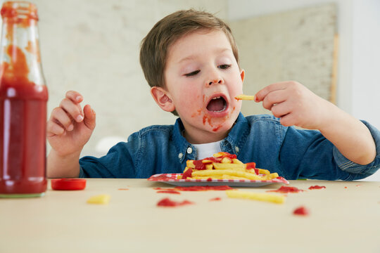 Germany, Munich, Boy eating French fries with ketchup