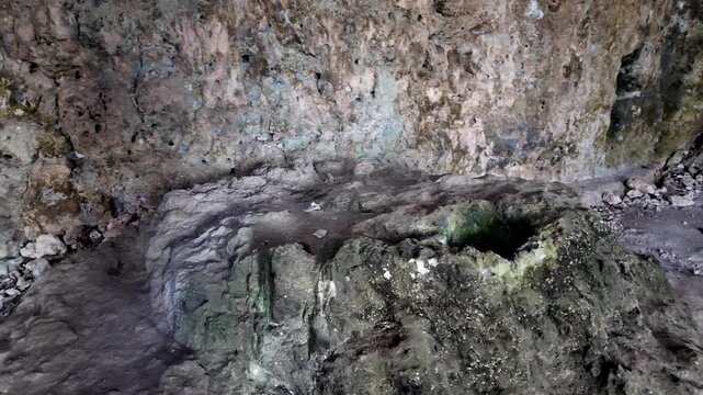 Ancient stone bath nestled in damp cave walls. Moss and water cling to rugged, weathered surfaces. History whispers through silent, echoing cavern space. Ideal for archaeology, tourism