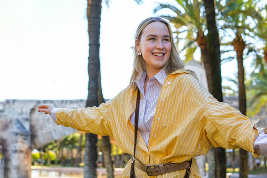 Solo female traveler, joyful vacation moment in sunny historic park with palm trees, authentic city escape, sightseeing, leisure travel and destination exploration