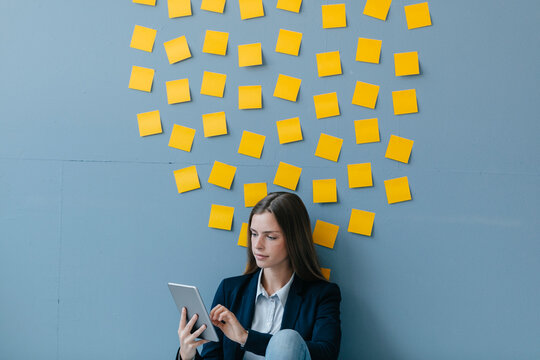Young businesswoman usig digital tabet, sitting under data cloud