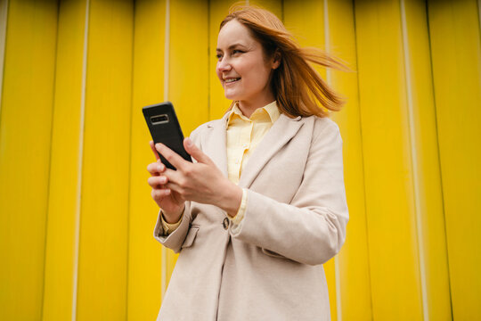 Smiling entrepreneur in blazer using smartphone outdoors