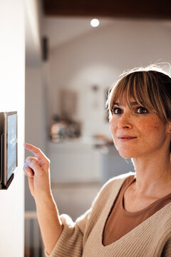 Contemplative woman using tablet PC mounted on wall at home