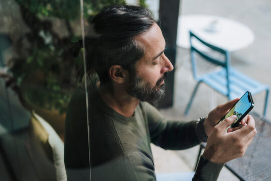 Man using smart phone sitting in cafe