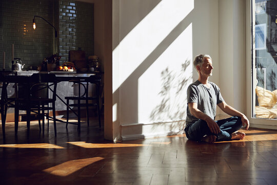 Mature man sitting on the floor at home meditating