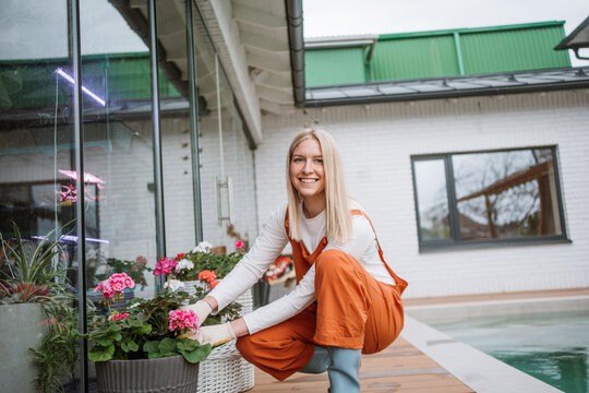 Smiling woman plants hydrangea flower in a pot outdoors