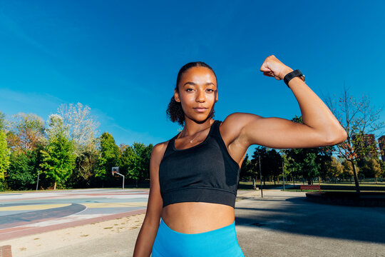 Young athlete flexing bicep in basketball court