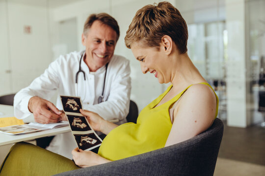 Pregnant woman discussing ultrasonic scans with her doctor