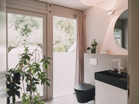 Modern luxury bathroom interior with black fixtures and large window