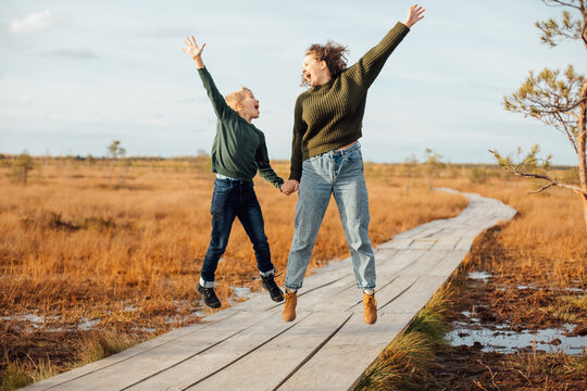 Mother and son enjoy a jump on a wooden boardwalk