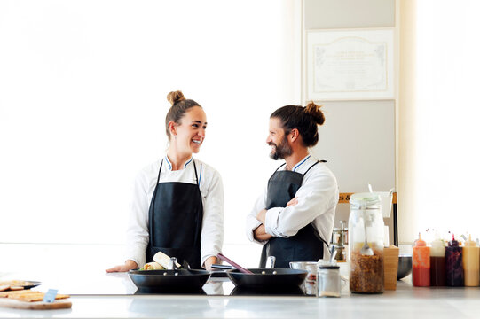 Smiling chefs talking while working in kitchen in restaurant