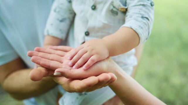 Child's small hands rest gently on adult hands. Parental care shown through tender touch. Scene captures warmth and protection. Ideal for themes of family, trust, or childhood innocence