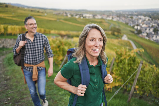 Thoughtful woman wearing backpack with man walking in background