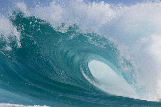 Powerful turquoise ocean wave crashing and forming a barrel