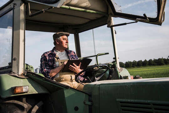 Farmer sitting in tractor using digital tablet