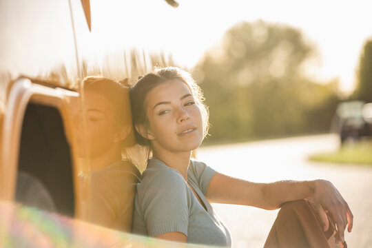 Pretty woman on a road trip with her camper, relaxing at the roadside