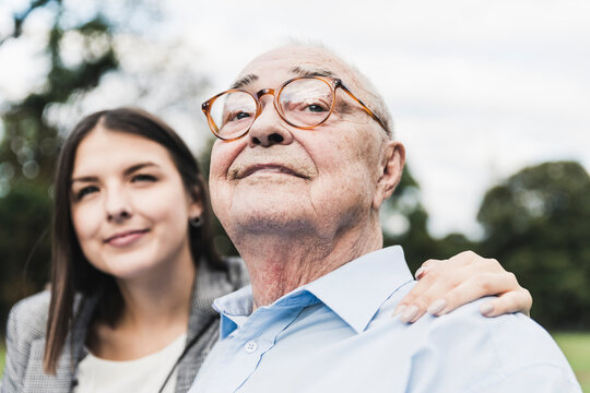 Portrait of self-confident senior man with granddaughter in the background
