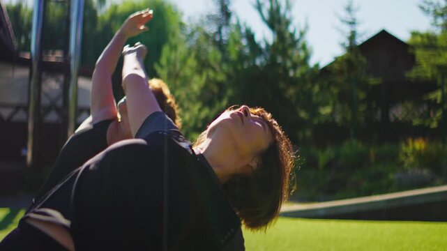Elderly women practicing slow motion Pilates stretches together on outdoor yoga mats in a peaceful green garden setting for gentle senior fitness and flexibility