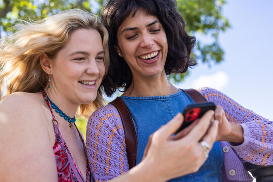 Happy friends look at a smartphone during a riverside walk in Berlin