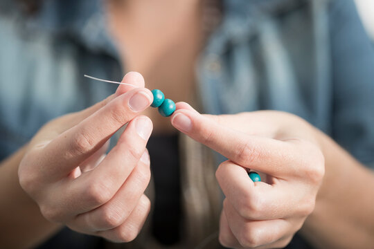 Close-up of woman stringing beads to create a necklace