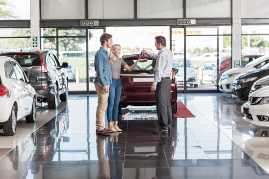 Car dealer giving key to clients