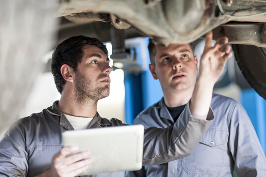 Two car mechanics at work in repair garage