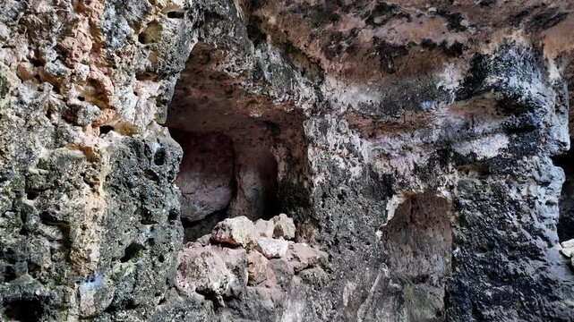 Xemxija, Malta 29.07.2026 - Heritage trail, Roman Baths, shelf like cut in the stone Dark cave walls show rough, textured surfaces. Greenish moss grows on damp, uneven stone. Light filters through nar