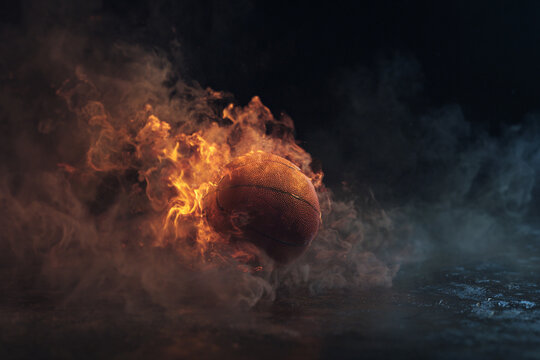 Dynamic action shot of basketball burning in bright orange flames and thick dark smoke trails flying fast over wet dark floor background, explosive power and competitive sports passion.
