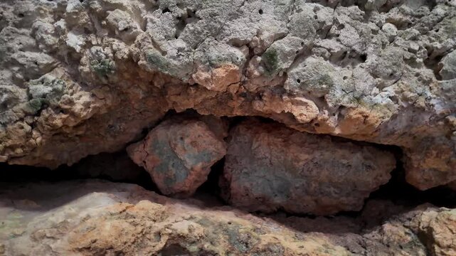 Xemxija, Malta 29.07.2026 - Heritage trail, Roman Baths, rocks between 2 walls an the ceiling Rugged stone walls frame a narrow cave entrance. Ancient earth tones and textures dominate the scene. No p