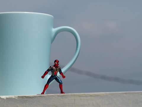 Indonesia - December 7, 2019 : Mini toy of action figure at outdoor with blurred background. Toy photography concept design with blue cup as a background. Spiderman character from Marvel film.