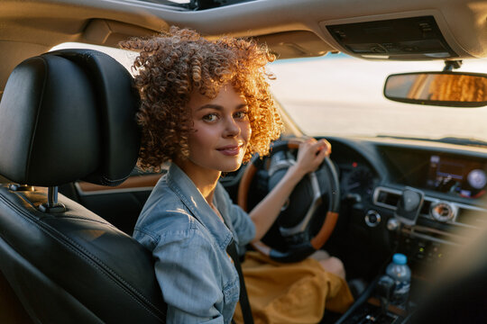 A smiling woman sits behind the wheel in a casual driving scene, showcasing everyday car life and confident, relaxed female lifestyle.