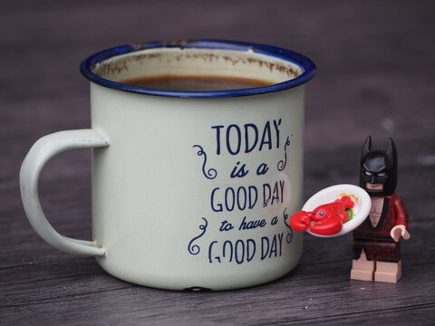 Indonesia - May 31, 2023 : Mini toy of action figure at table with blurred background. Miniature photography concept design. Minifigure of Batman character with pan and lobster.
