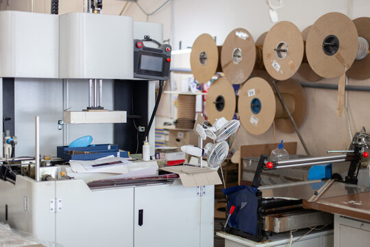 Professional industrial printing and binding machine in workshop, with various rolls of materials. Production, industrial printing, manufacturing, printing industry, craftsmanship, technology.