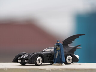 Fototapeta premium Indonesia - December 16, 2018 : Mini toy of action figure at table with blurred background. Macro toy photography concept design. Minifigure of Batman character from DC Comics film with batmobile.