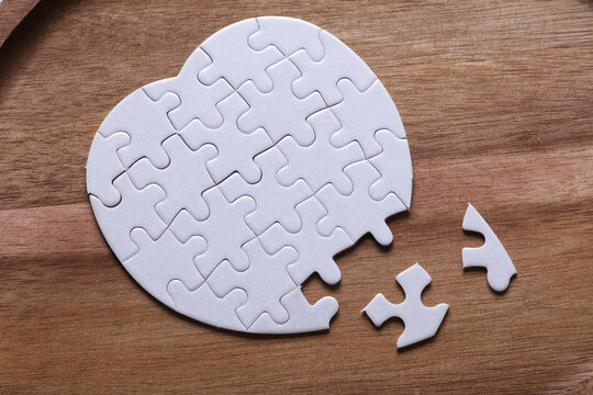 White blank heart-shaped puzzle on a wooden tray. Love, healthcare concept.