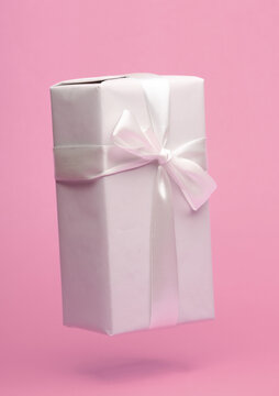 White gift box with bow mockup floating on pink background