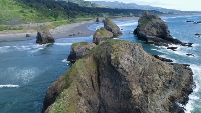 A cinematic drone footage glides forward above sea-stacks along Ariya&rsquo;s Beach, revealing towering sea stacks, Pacific surf and rugged shoreline near Branson Carlton&rsquo;s View on Oregon&rsquo;s southern coast.