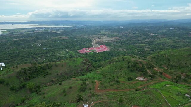 High altitude aerial view of wind turbines in Pililla, Rizal with rolling mountains, vegetation, and rural communities in the background.
