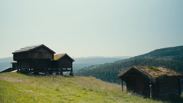 Traditional Norwegian wooden storehouses with grass roofs overlooking forested hills in Telemark, showcasing Nordic heritage, rural architecture and history.