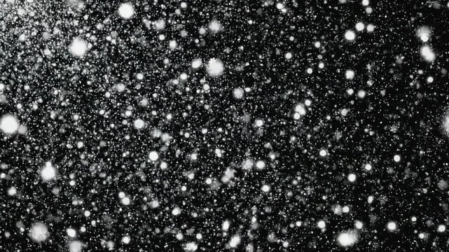 Superposici&oacute;n de copos de nieve blancos cayendo sobre fondo negro con efecto bokeh. Ideal para composiciones navide&ntilde;as, videos invernales, efectos visuales y motion graphics.