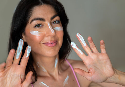 Beautiful Woman applying sunscreen lotion on her face
