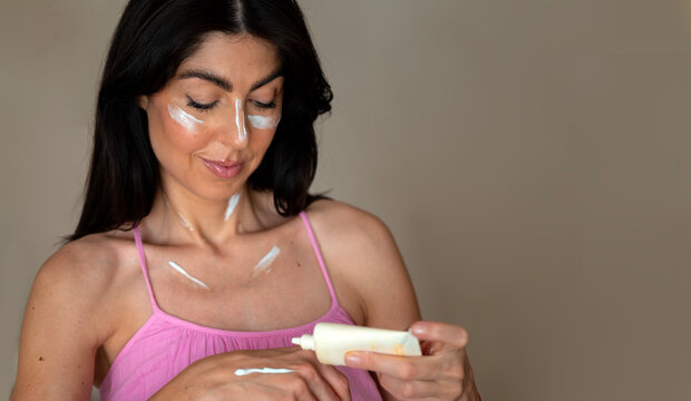 Beautiful Woman applying sunscreen lotion on her hand
