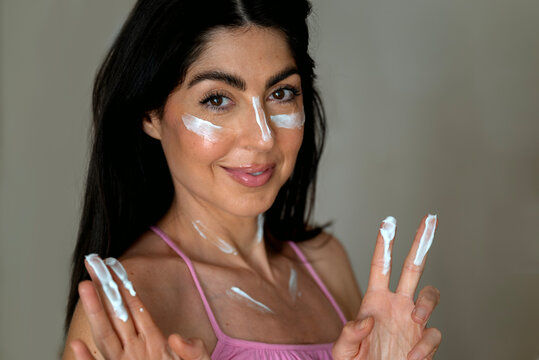 Beautiful Woman applying sunscreen lotion on her face