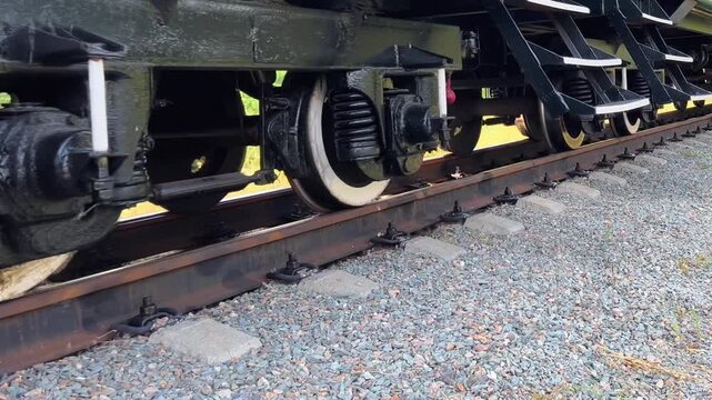 Narrow gauge railway wheels roll slowly along steel track