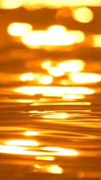Radiant sunlight glimmers upon rolling river water during a peaceful sunset. Soft focus close-up macro shot.