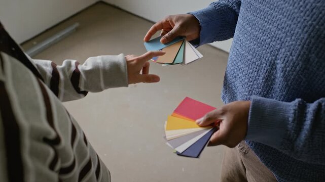 African American man holding color swatches while Caucasian client pointing at samples during home renovation planning. Clip is ideal for interior design services and DIY home improvement commercials