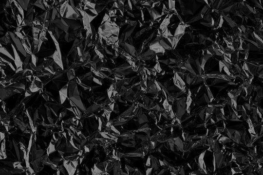Shiny black foil texture background, pattern of wrapping paper with crumpled and wavy.