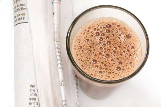 Close-up of Indian newspaper with glass of chai isolated over white background 