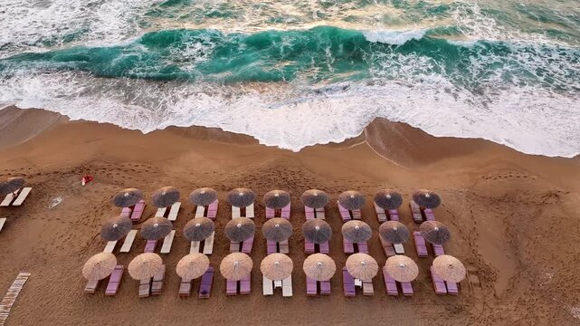 Aerial top view of a beach in Greece with sunbed and sunshade at sunset