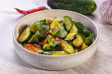 Obraz premium Smashed cucumber salad with sesame seeds and chili flakes in ceramic bowl